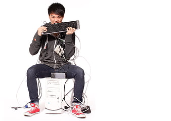 Frustrated man biting computer keyboard in anger