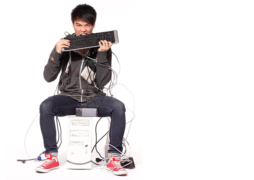 Frustrated man biting computer keyboard in anger