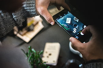 Hands holding smartphone taking photo of coffee and cards