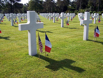 White marble crosses in military cemetery with US and French flags