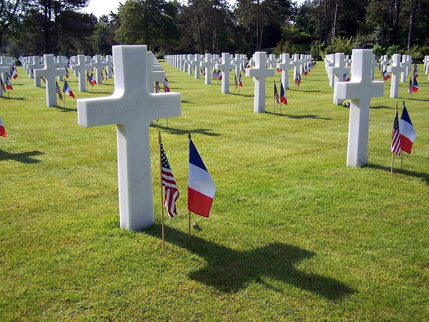 White marble crosses in military cemetery with US and French flags