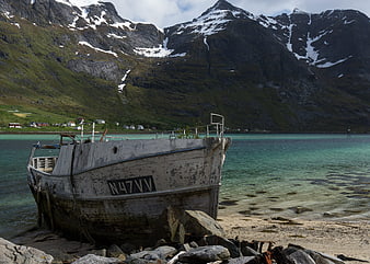 Old weathered fishing boat on a sandy beach in a Norwegian fjord