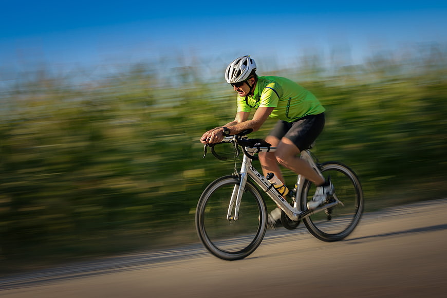 Male Cyclist Riding Road Bike With Motion Blur Background