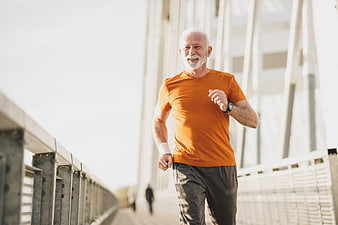Senior man jogging on bridge in orange shirt
