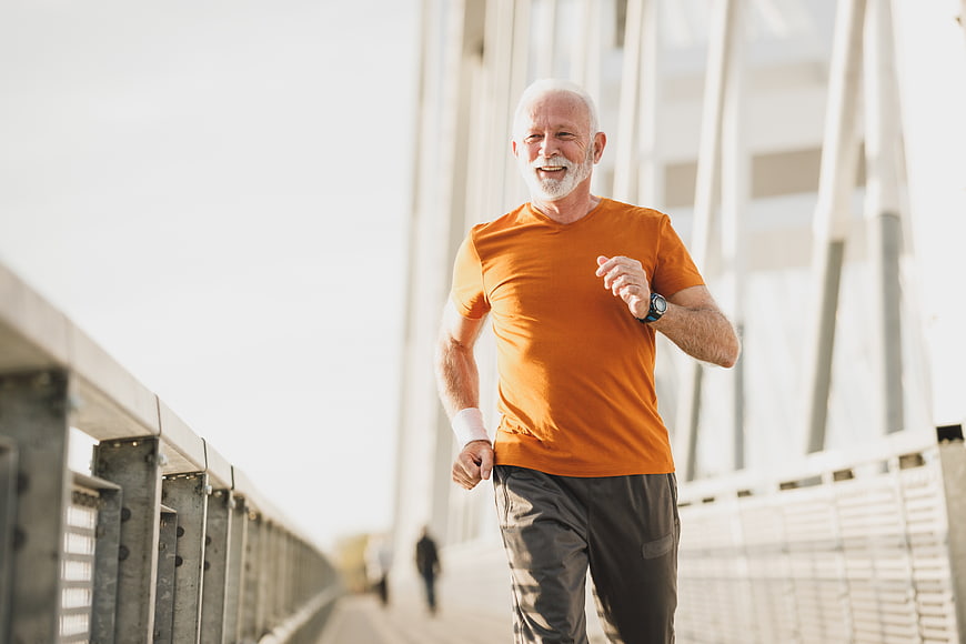 Senior man jogging on bridge in orange shirt