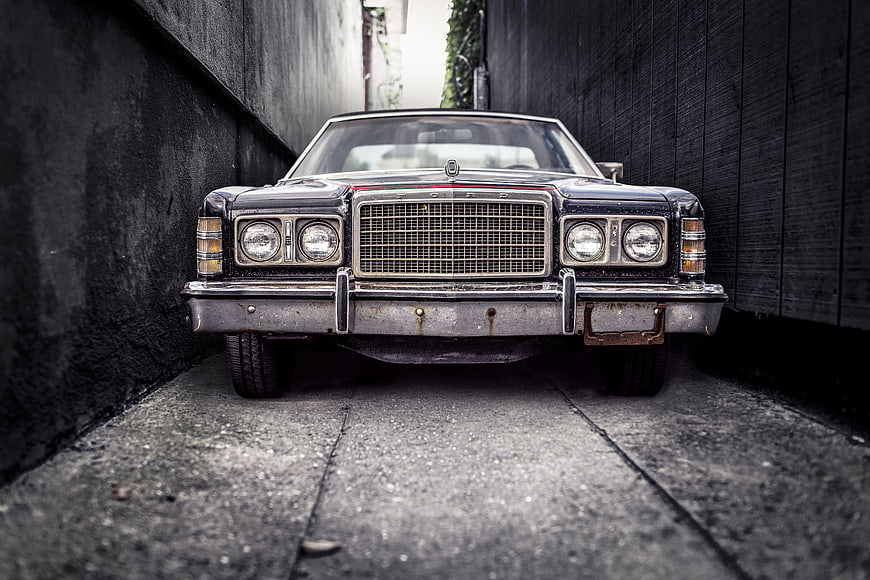 Front view of vintage black Ford car in narrow alley