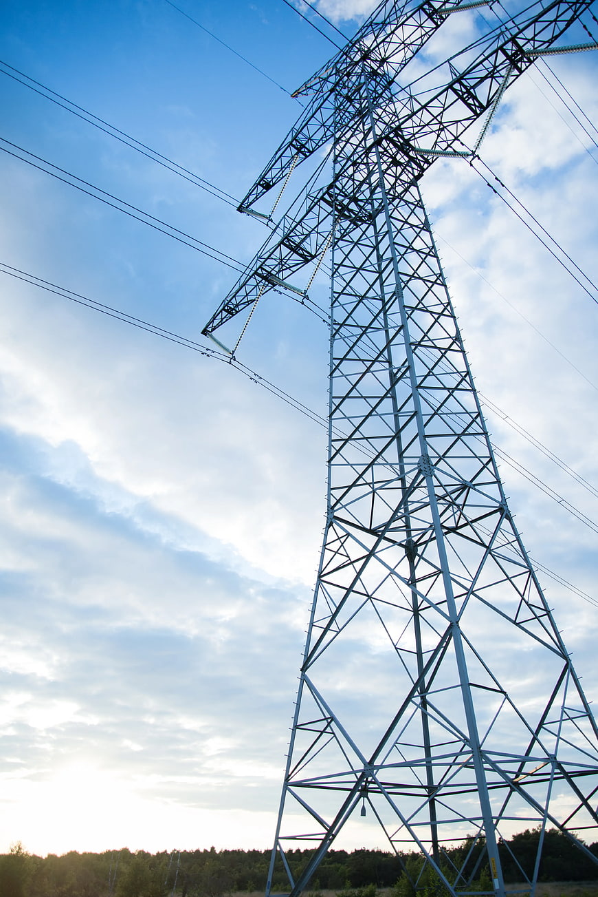 Low angle view of high voltage transmission tower against blue sky