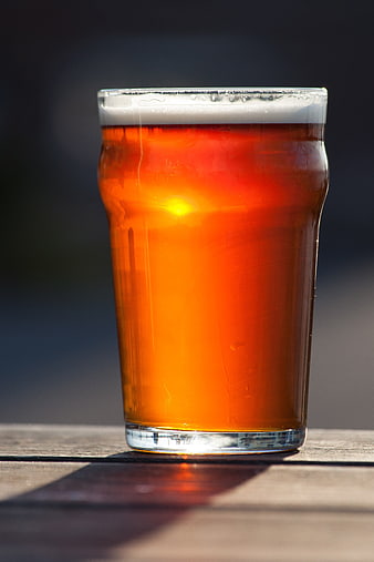 Glass of Amber Ale Beer on Wooden Table in Sunlight