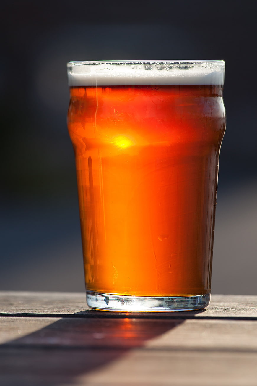 Glass of Amber Ale Beer on Wooden Table in Sunlight