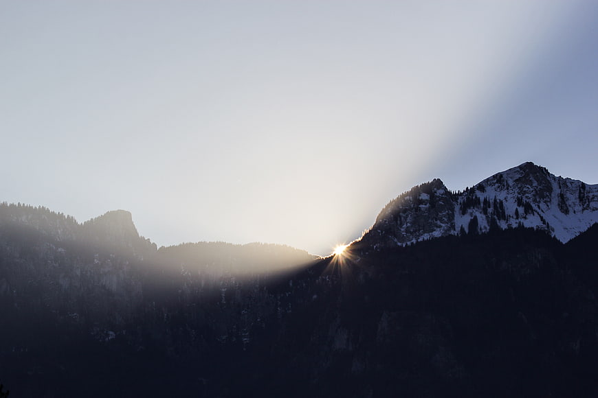 Sunburst rays over snowy mountain peaks at sunrise