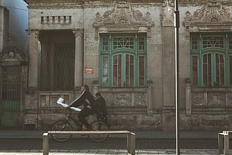 Man riding bicycle past historic building facade