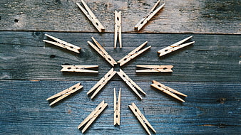 Wooden Clothespins Arranged in Snowflake Pattern on Blue Wood