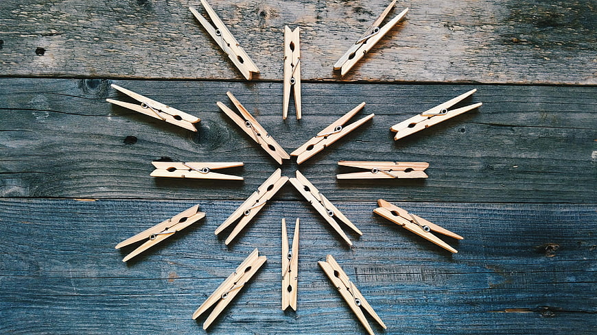 Wooden Clothespins Arranged in Snowflake Pattern on Blue Wood