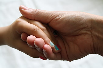 Close-up of adult and child holding hands with painted nails