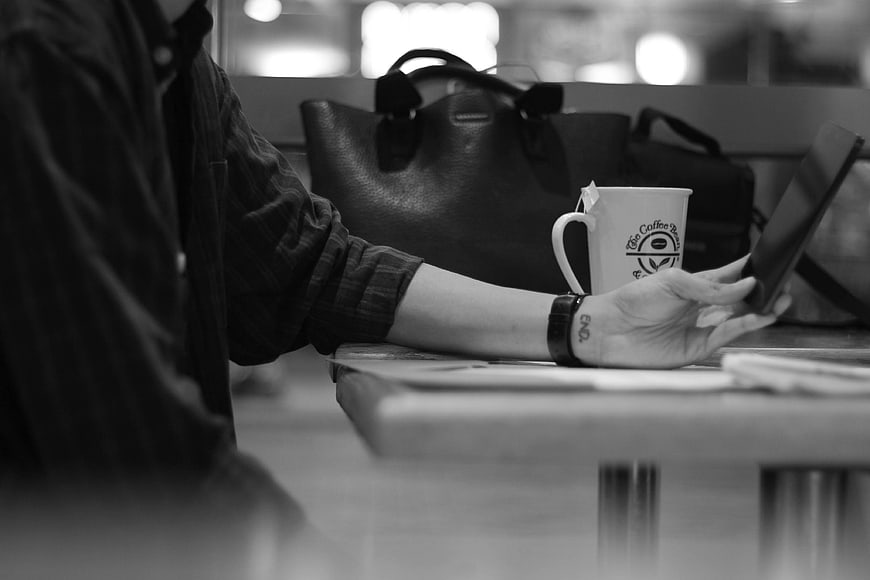 Black and white photo of woman using smartphone at cafe