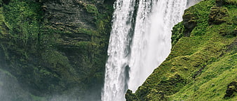 Majestic waterfall cascading down moss-covered green cliffs
