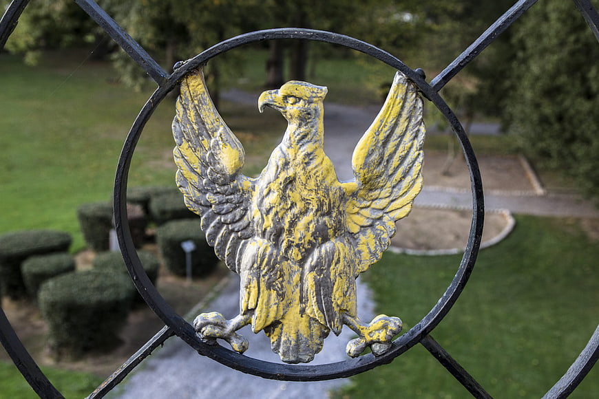 Weathered yellow iron eagle sculpture on black metal fence