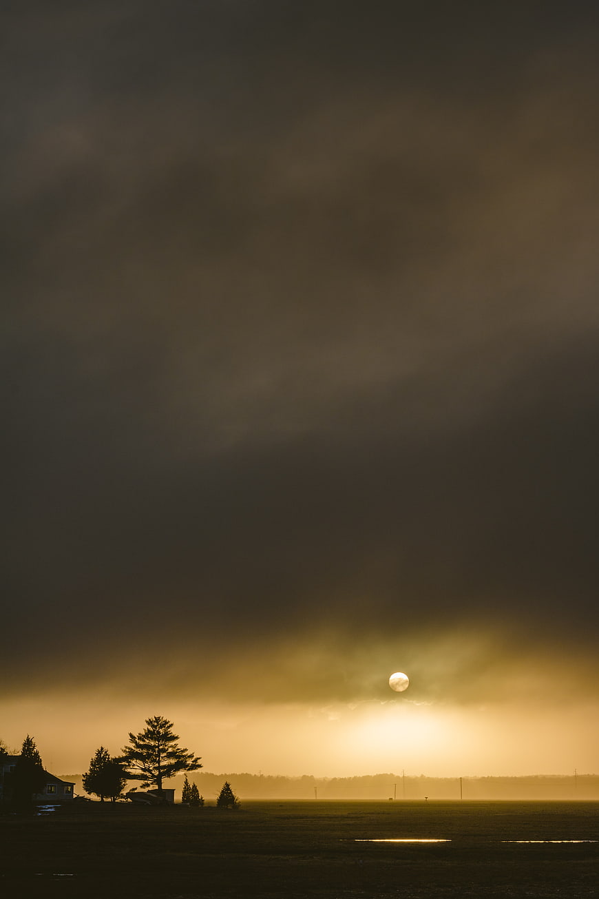 Dramatic Moonrise Over Silhouetted Rural Landscape