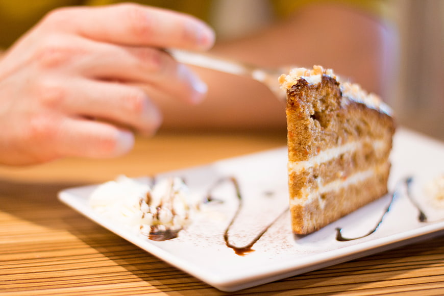 Close-up of layered cake slice with fork on white plate