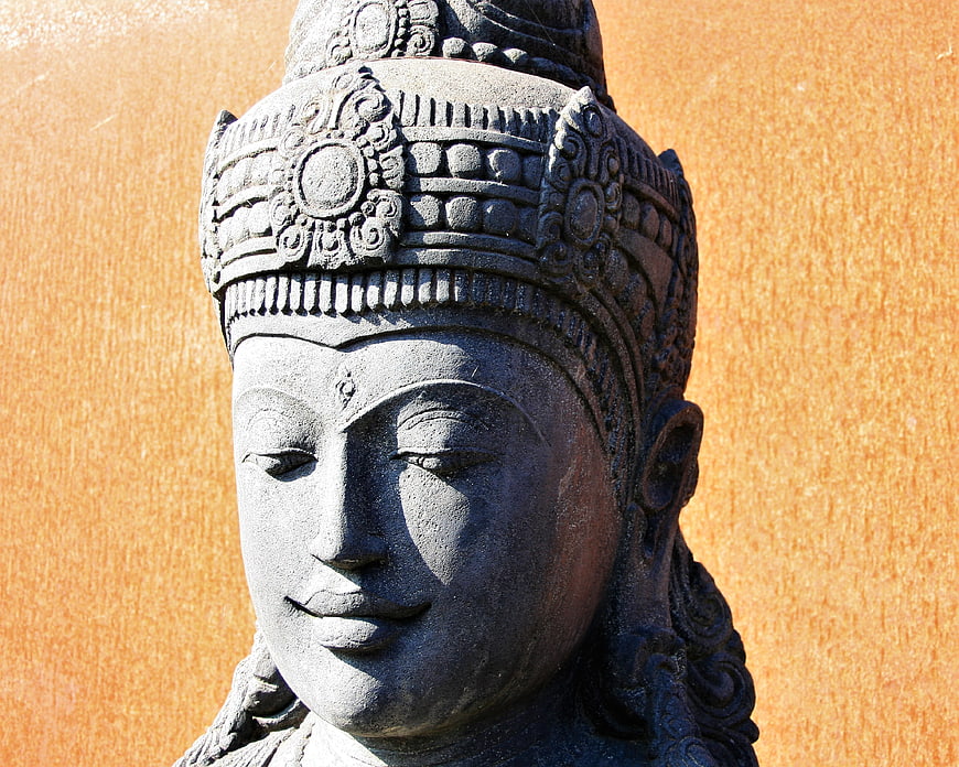 Close-up of serene stone Buddha head sculpture against orange wall