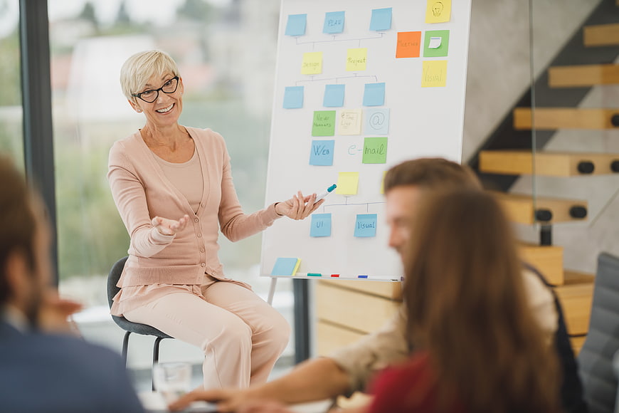 Senior Business Woman Leading Strategy Meeting with Whiteboard