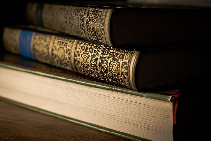 Stack of vintage hardcover books with gold embossed spines