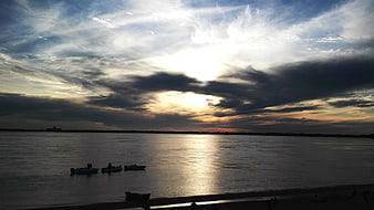 Dramatic Sunset Over River with Silhouetted Boats