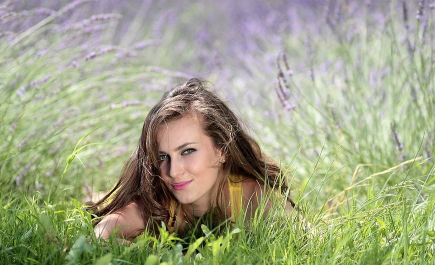 Young woman lying in a lavender field with green grass