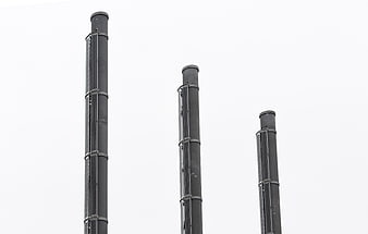Three tall industrial smokestacks against white sky