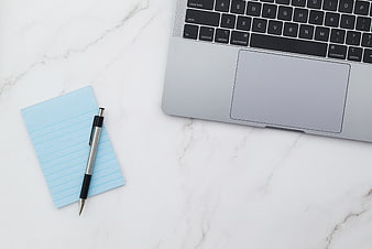 Minimalist workspace with laptop, pen, and notepad on marble