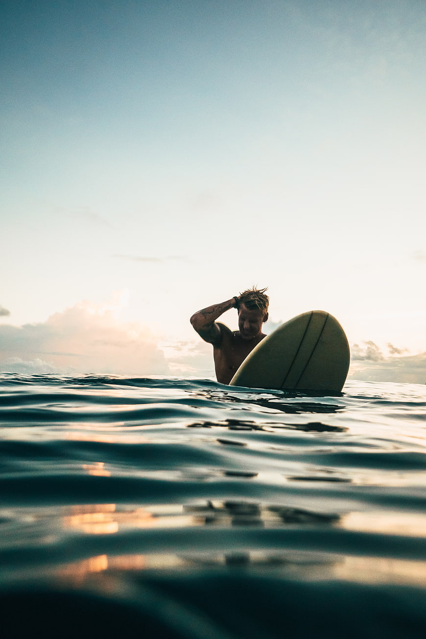 Surfer in Ocean Water at Sunset with Surfboard