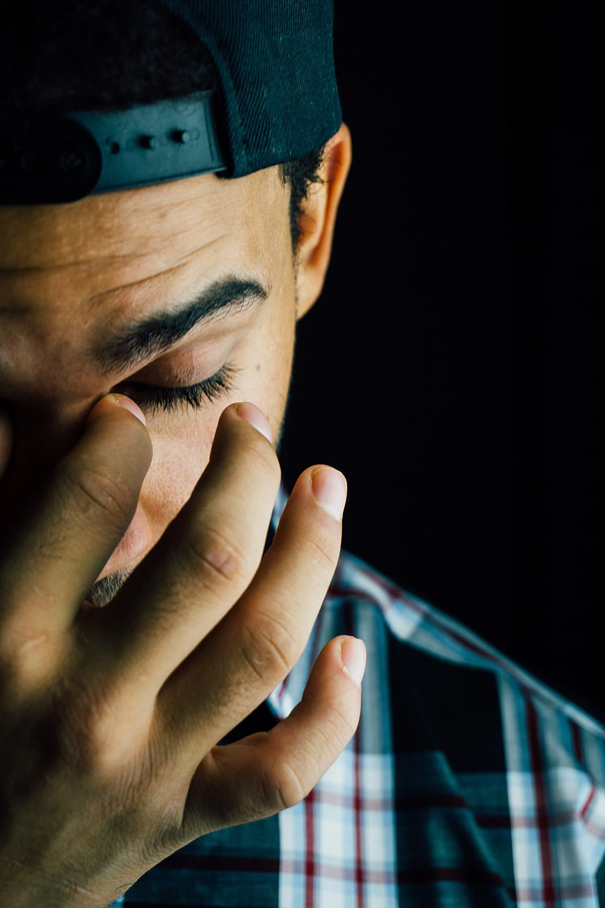 Close-up of man rubbing nose bridge in plaid shirt