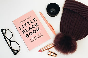 Flat lay of Little Black Book, glasses, lipstick, and beanie
