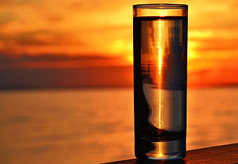 Glass of Water with Sunset Reflection by the Sea