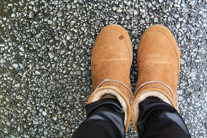 Top-down view of brown suede winter boots on wet pavement