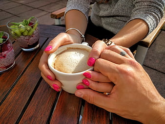 Couple holding coffee cup and hands on wooden table