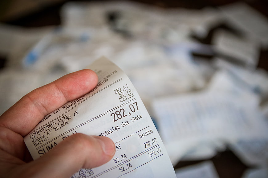Hand holding a printed receipt with financial figures and blurred background