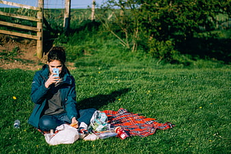 Woman taking selfie during outdoor picnic on grass