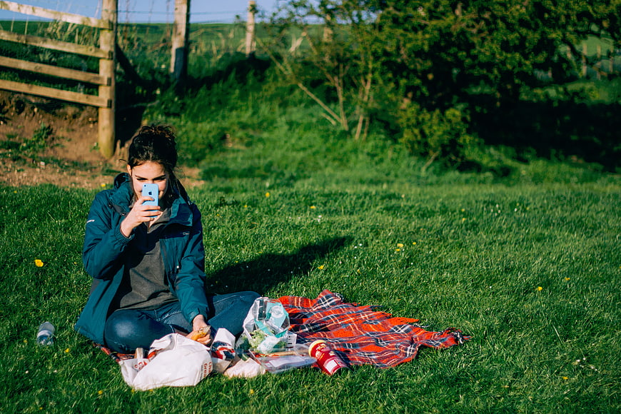 Woman taking selfie during outdoor picnic on grass