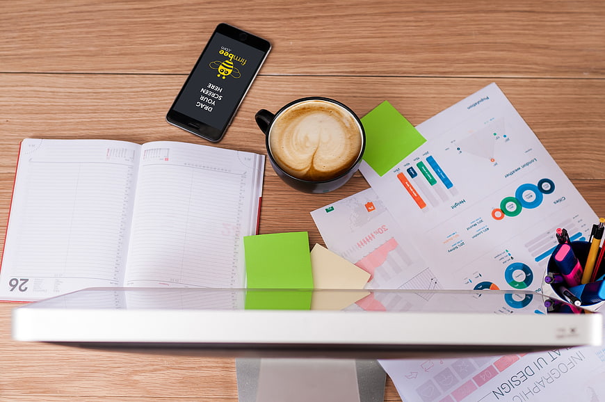 Top view of office desk with coffee, smartphone, and business charts