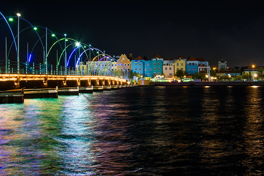 Colorful waterfront buildings and illuminated bridge at night