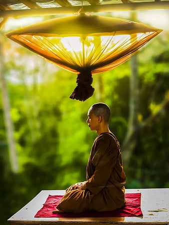 Monk Meditating Under Yellow Umbrella in Nature