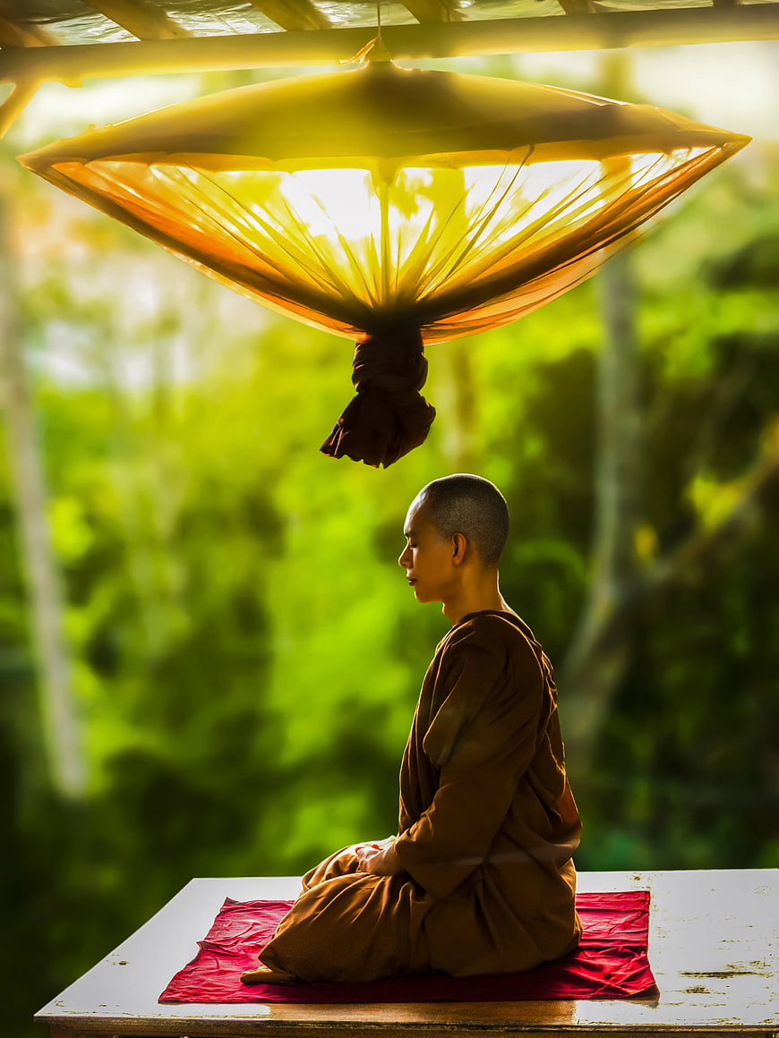 Monk Meditating Under Yellow Umbrella in Nature