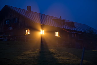 Rustic wooden house with glowing windows at night