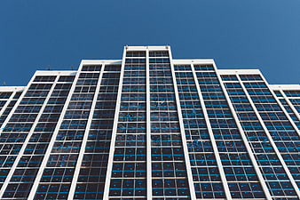 Low angle view of modern glass skyscraper against blue sky