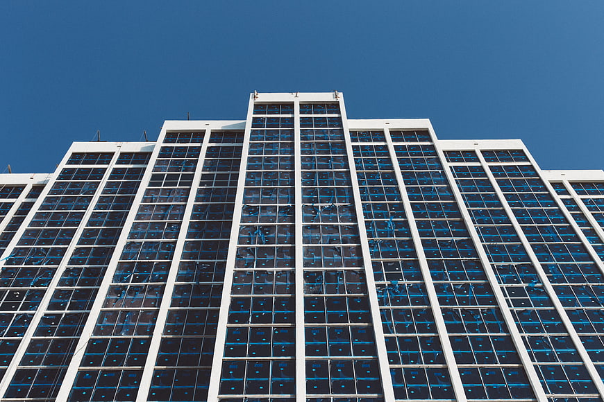 Low angle view of modern glass skyscraper against blue sky