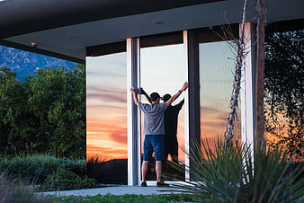 Man Opening Glass Doors to Sunset View