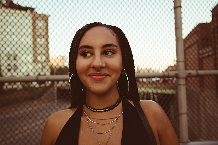 Stylish woman with braids smiling in urban setting