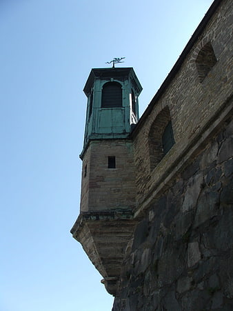 Low angle view of historic stone fortress tower against blue sky