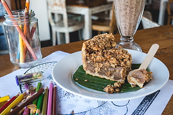 Slice of crumble cake with smoothie and colored pencils on table